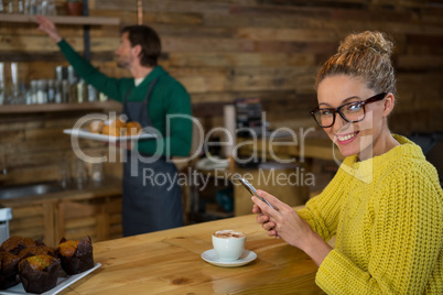 Portrait of happy woman using mobile phone in coffee shop