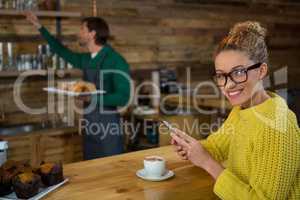 Portrait of happy woman using mobile phone in coffee shop