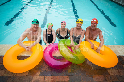 Senior swimmers with inflatable rings standing at poolside