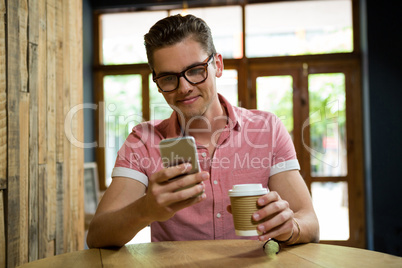 Man using mobile phone at table in coffee shop