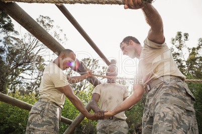 Military soldiers with hands stacked during obstacle training
