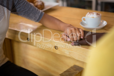 Multi ethnic couple holding hands in coffee house