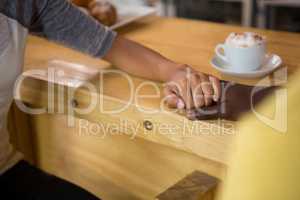 Multi ethnic couple holding hands in coffee house