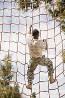 Military soldier climbing net during obstacle course