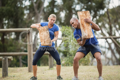People carrying heavy wooden logs during obstacle course