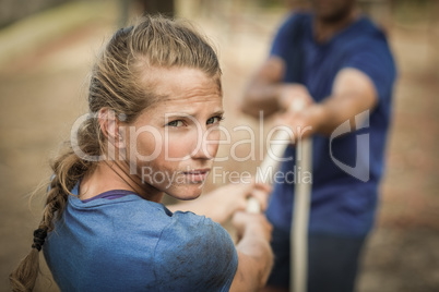 Man and woman playing tug of war during obstacle course