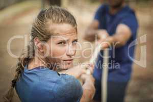 Man and woman playing tug of war during obstacle course