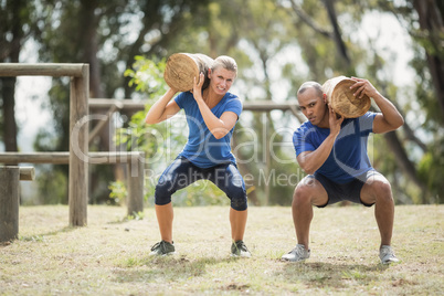 People carrying heavy wooden logs during obstacle course