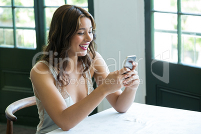 Smiling woman using mobile phone in restaurant