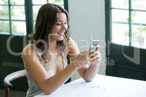 Smiling woman using mobile phone in restaurant