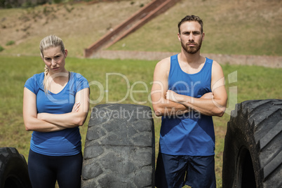 Portrait of fit and woman standing with arms crossed beside tire