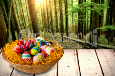 Composite image of multi colored easter eggs in wicker basket