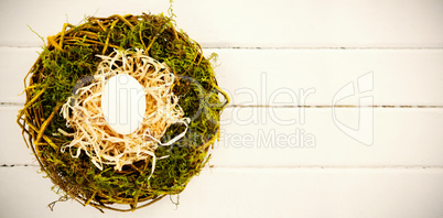 White egg in nest on wooden surface