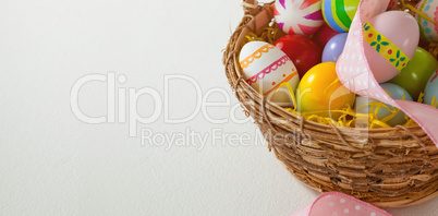 Various Easter eggs with ribbon in wicker basket