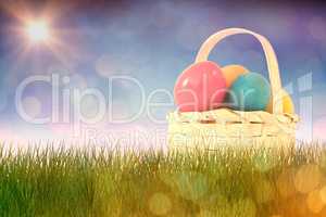 Composite image of easter eggs in wicker basket