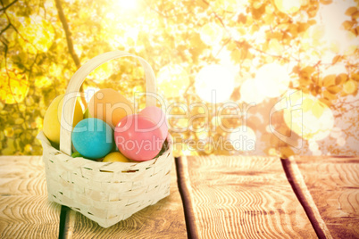 Composite image of mulit colored easter eggs in wicker basket