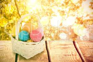 Composite image of mulit colored easter eggs in wicker basket