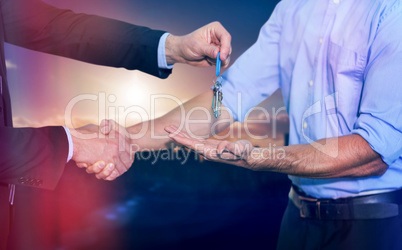 Composite image of businessman shaking hands and giving keys