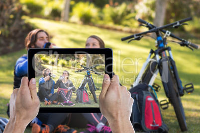 Composite image of cropped hand holding digital tablet