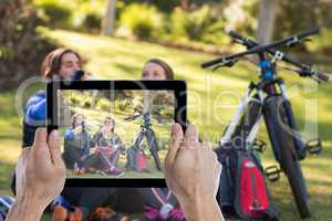 Composite image of cropped hand holding digital tablet