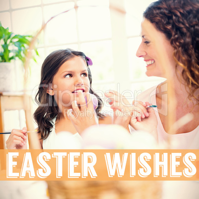 Composite image of happy mother and daughter painting easter eggs