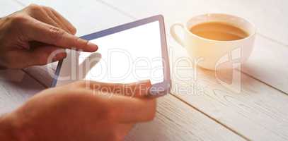 Person holding tablet on wooden desk
