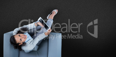 Composite image of woman on her tablet looking up