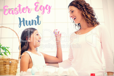 Composite image of happy girl showing easter egg to her mother