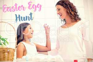 Composite image of happy girl showing easter egg to her mother