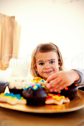 Smiling little girl eating confectionery at home