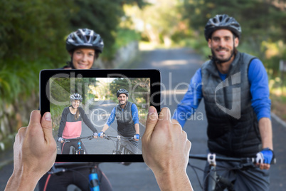 Composite image of cropped hand holding digital tablet