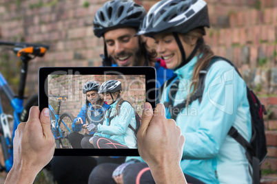 Composite image of cropped hand holding digital tablet