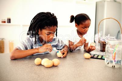 Concentrated siblings painting eggs