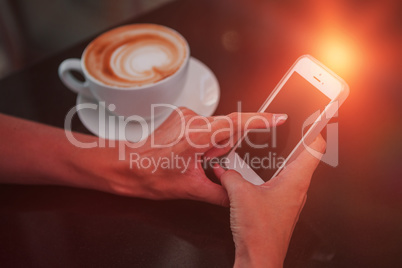 Woman having coffee and using her phone
