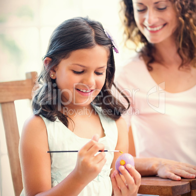 Happy mother and daughter painting easter eggs