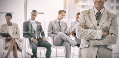 Serious businessman standing in  front of business people