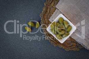 Green olives in a white bowl, top view