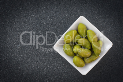 Large green olives in a white bowl