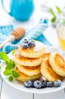 Cottage cheese pancakes with honey and blueberry on white background, breakfast or lunch