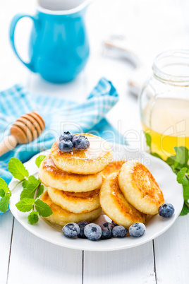 Cottage cheese pancakes with honey and blueberry on white background, breakfast or lunch