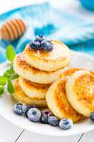 Cottage cheese pancakes with honey and blueberry on white background, breakfast or lunch