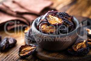 Prune, dried plums fruits on dark rustic wooden background