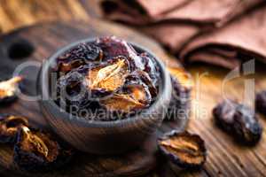 Prune, dried plums fruits on dark rustic wooden background