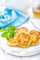 Cottage cheese fritters on white wooden background closeup