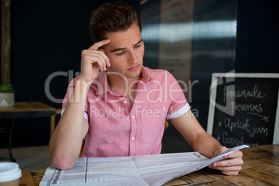 Man reading newspaper at table in coffee shop