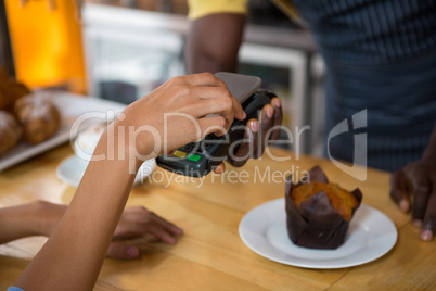 Customer paying barista through smart phone in coffee shop