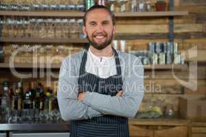 Male barista standing arms crossed in coffee shop