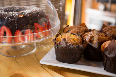 Muffins and cake on counter in coffee shop
