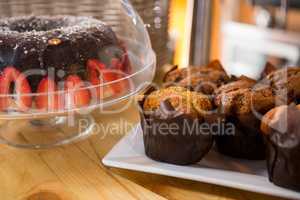 Muffins and cake on counter in coffee shop