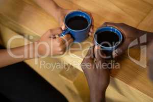 Couple hands holding coffee cups at table